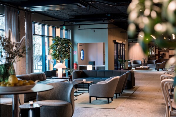 A modern lounge area with sofas, tables, and a large potted plant. - Quality Hotel Grand Boras (Borås)