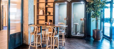 Un interior moderno con una mesa y sillas de madera, una planta en maceta y un vidrio que da al exterior.