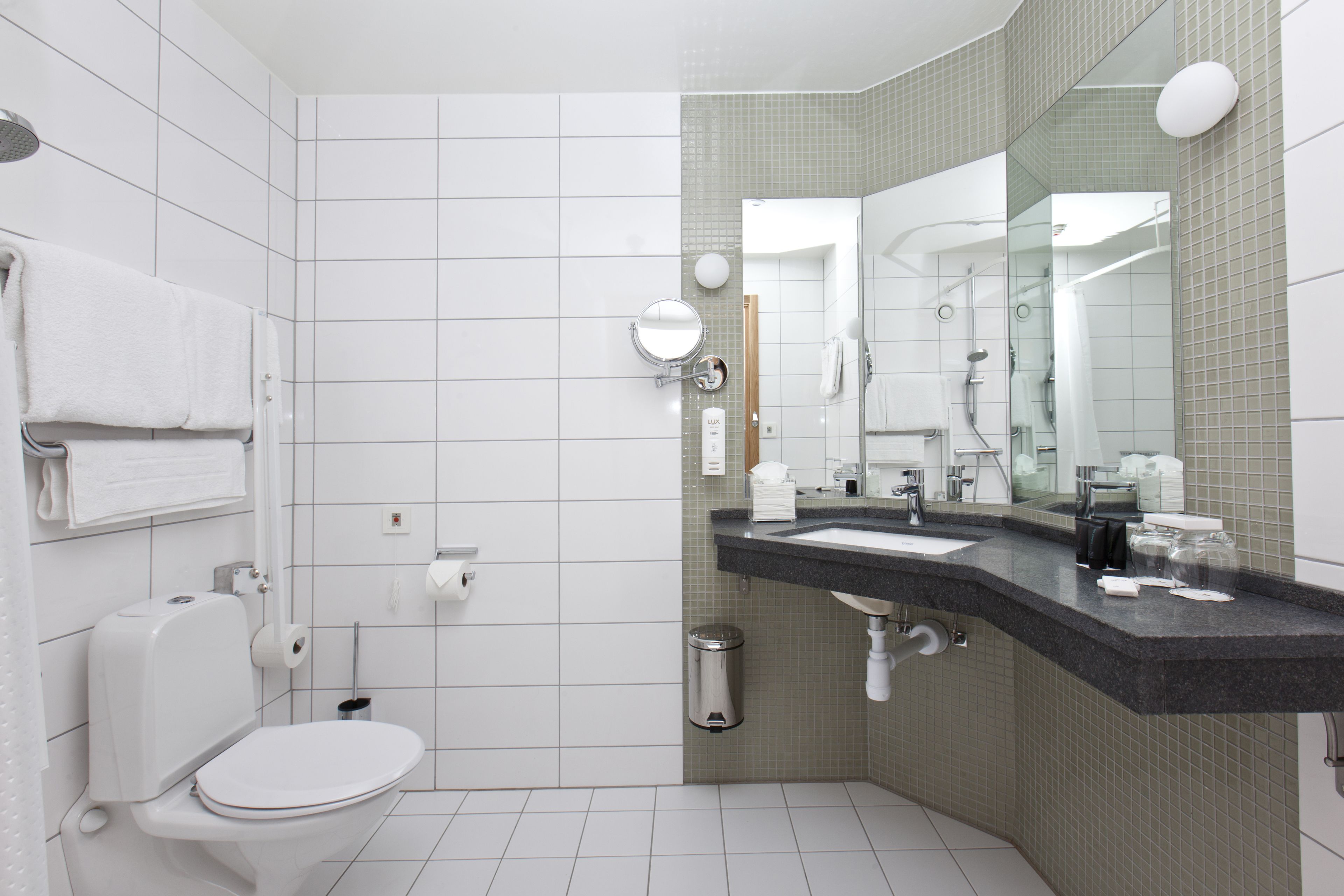 Een moderne badkamer met een wit toilet, een wastafel met spiegel en een douchegedeelte.