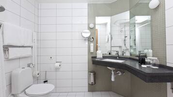 Een moderne badkamer met een wit toilet, een wastafel met spiegel en een douchegedeelte.