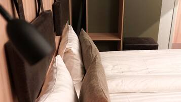 A bed with a wooden headboard, white bedding, and two pillows.