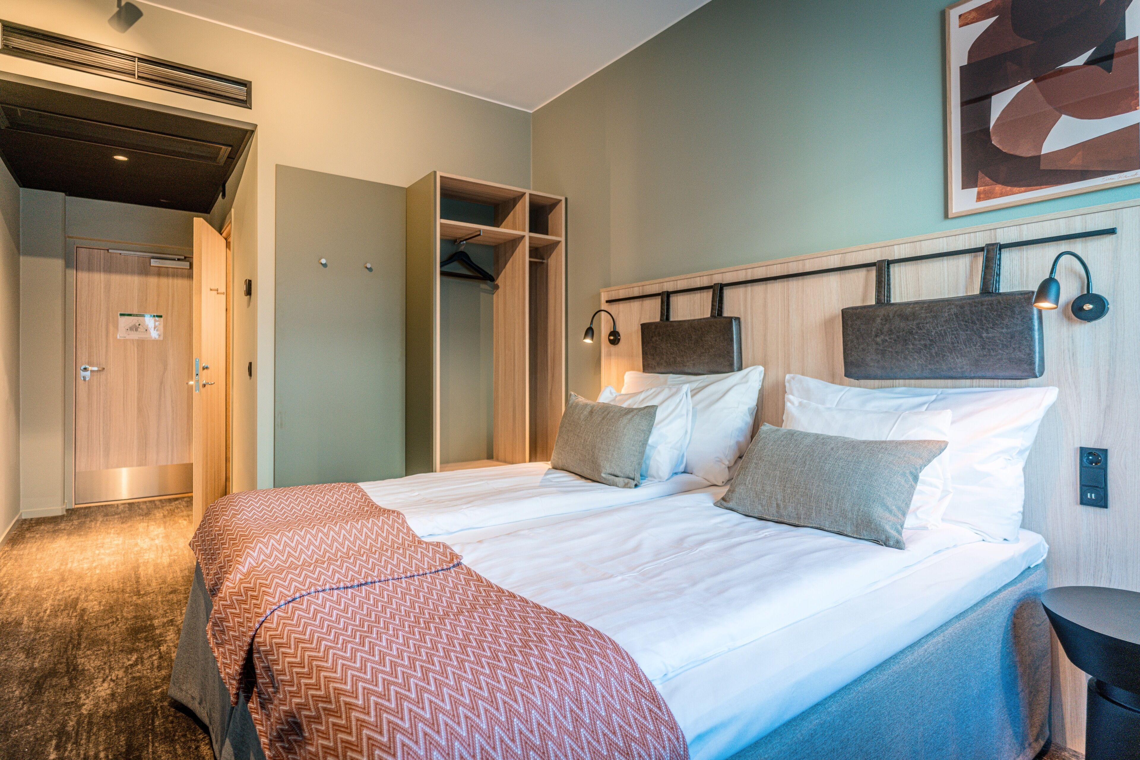 Een hotelkamer met een groot bed, een kledingkast en een bureau.