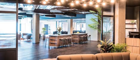 A modern office space with a central bar area, seating, and large windows.