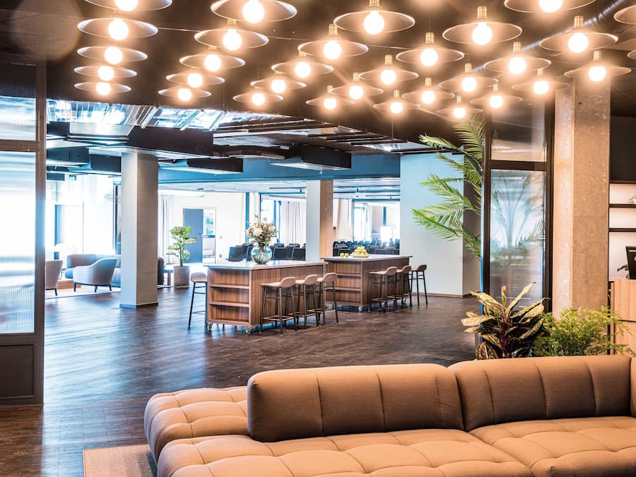 A modern office space with a central bar area, seating, and large windows.
