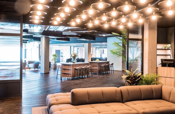 Un espacio de oficina moderno con una barra central, asientos y ventanas amplias.
