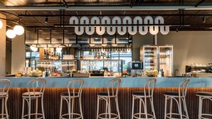 A bar area with a counter, stools, and shelves stocked with bottles. - Quality Hotel Grand Boras (Borås)