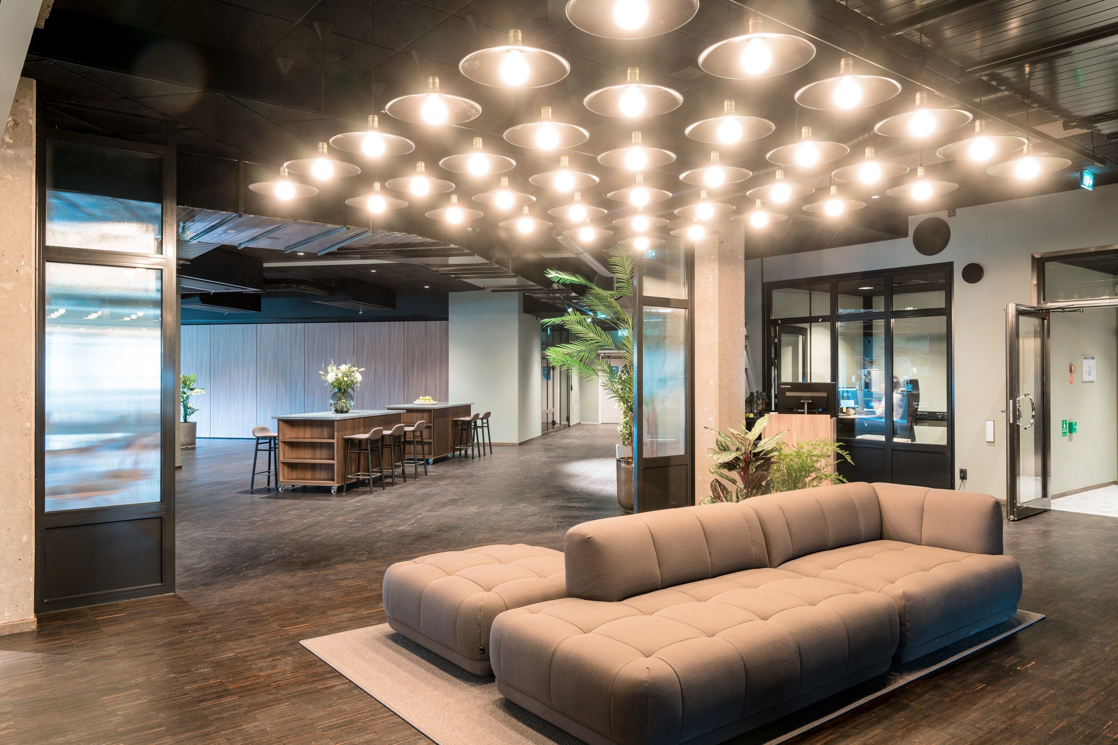A modern office space with a large sofa, a dining area, and a reception desk.