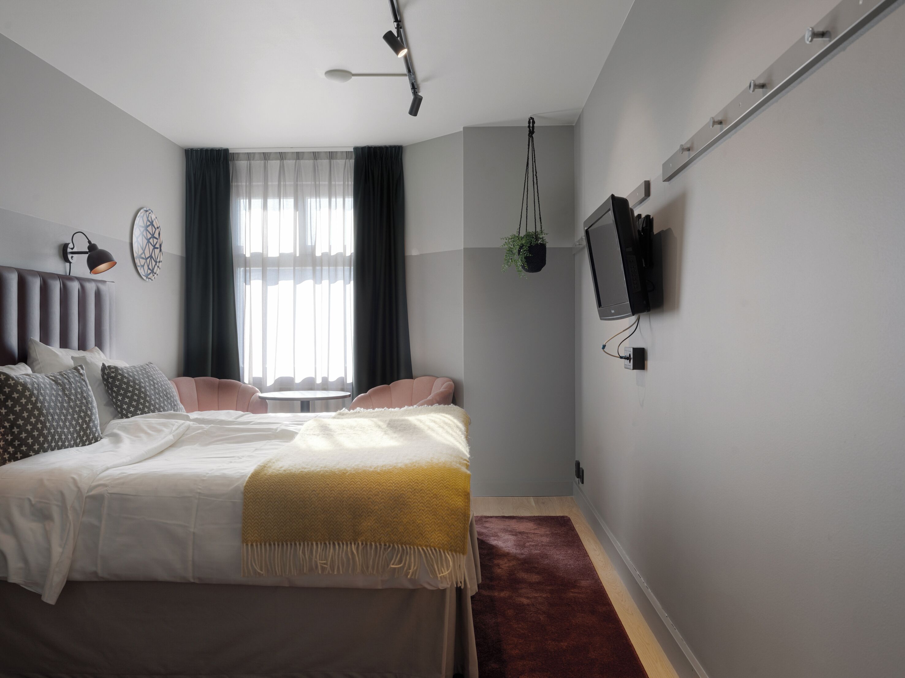 Un dormitorio moderno con cama, lámparas de noche, televisor y ventana con cortinas.