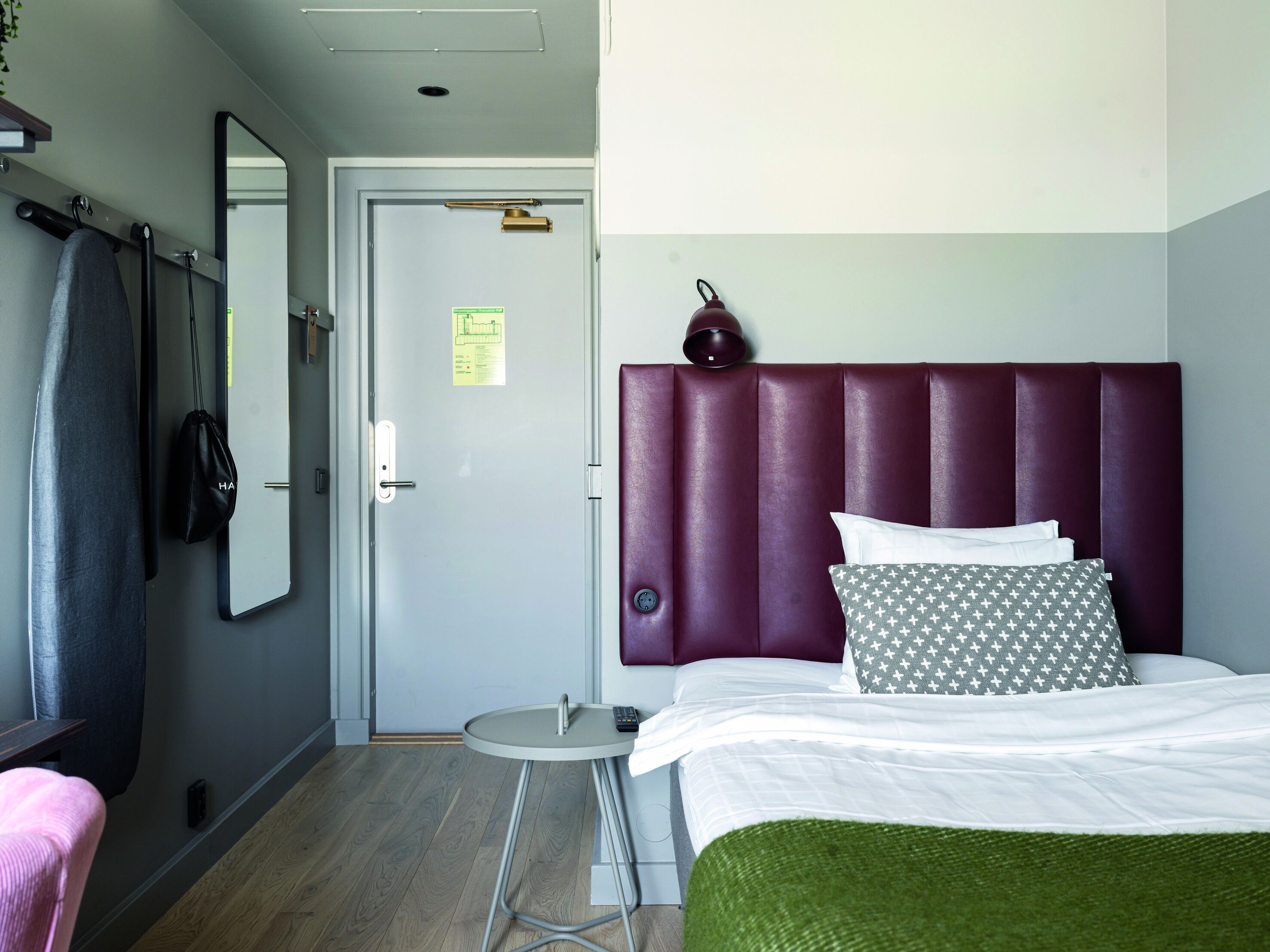 Une chambre d’hôtel avec un lit, une table ronde, un miroir et une porte.