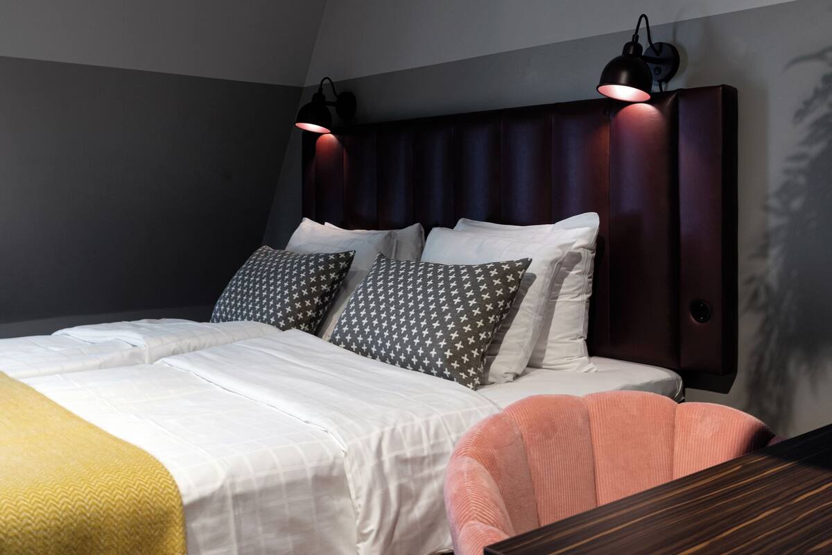 Ein modernes Schlafzimmer mit einem großen Bett, zwei Nachttischlampen, einem hölzernen Kopfteil und einem kleinen Tisch.