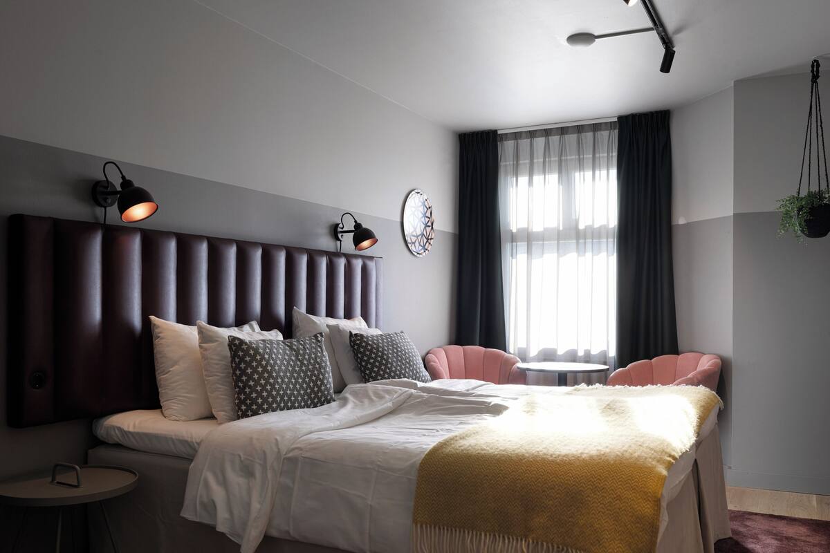 Ein modernes Schlafzimmer mit einem großen Bett, zwei Nachttischen, einem kleinen runden Tisch und einem Sessel.