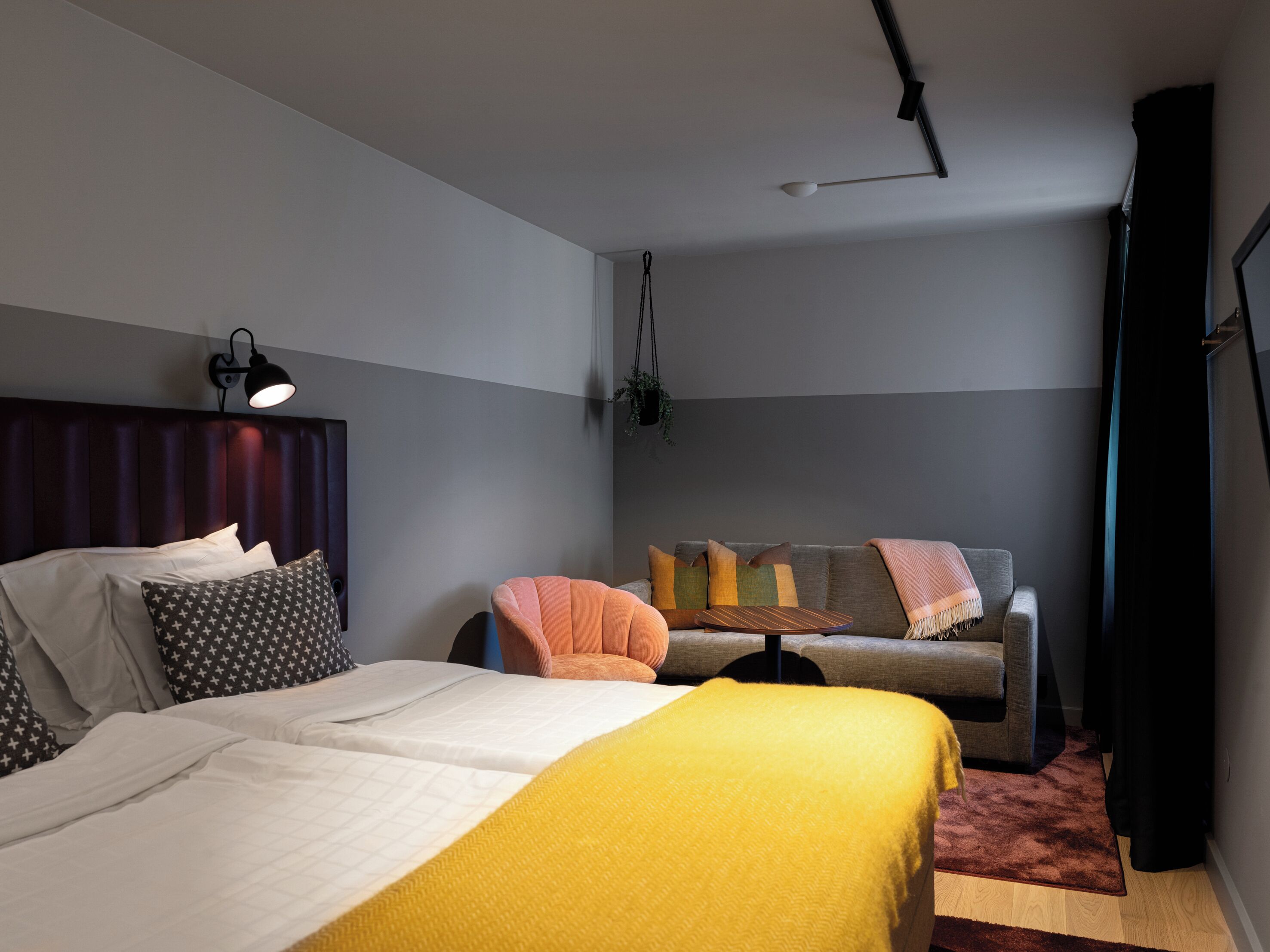 Un dormitorio moderno con una cama, un sofá y una planta colgante.