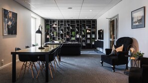 A modern office space with a long table, chairs, a sofa, and a bookshelf. - Comfort Hotel Skelleftea (Skelleftea)