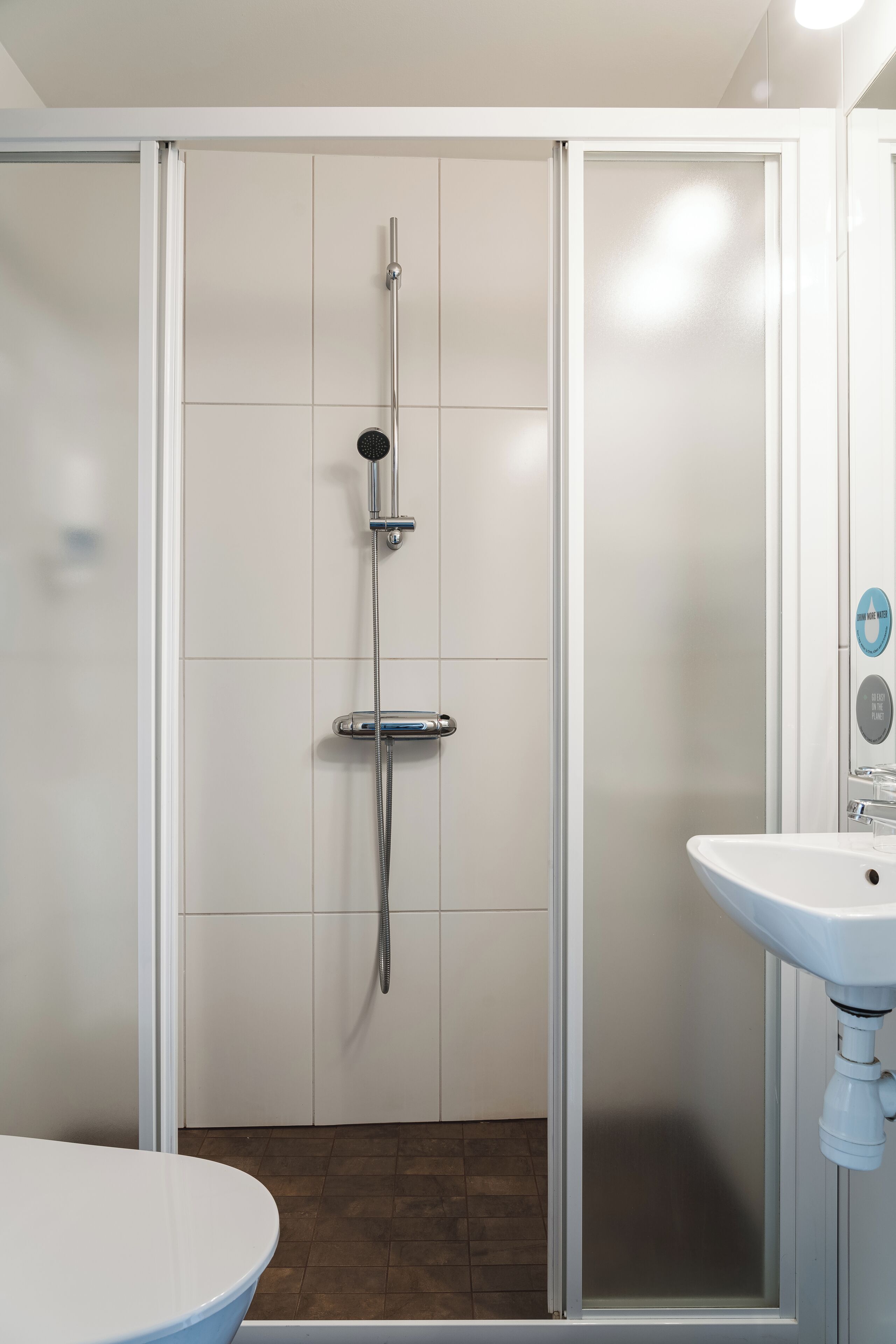 A modern bathroom with a shower enclosure, a sink, and a mirror.