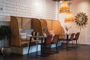 A cozy seating area with a woven sofa, a dining table, and chairs, accompanied by a vase and a potted plant. - Comfort Hotel Skelleftea (Skelleftea)