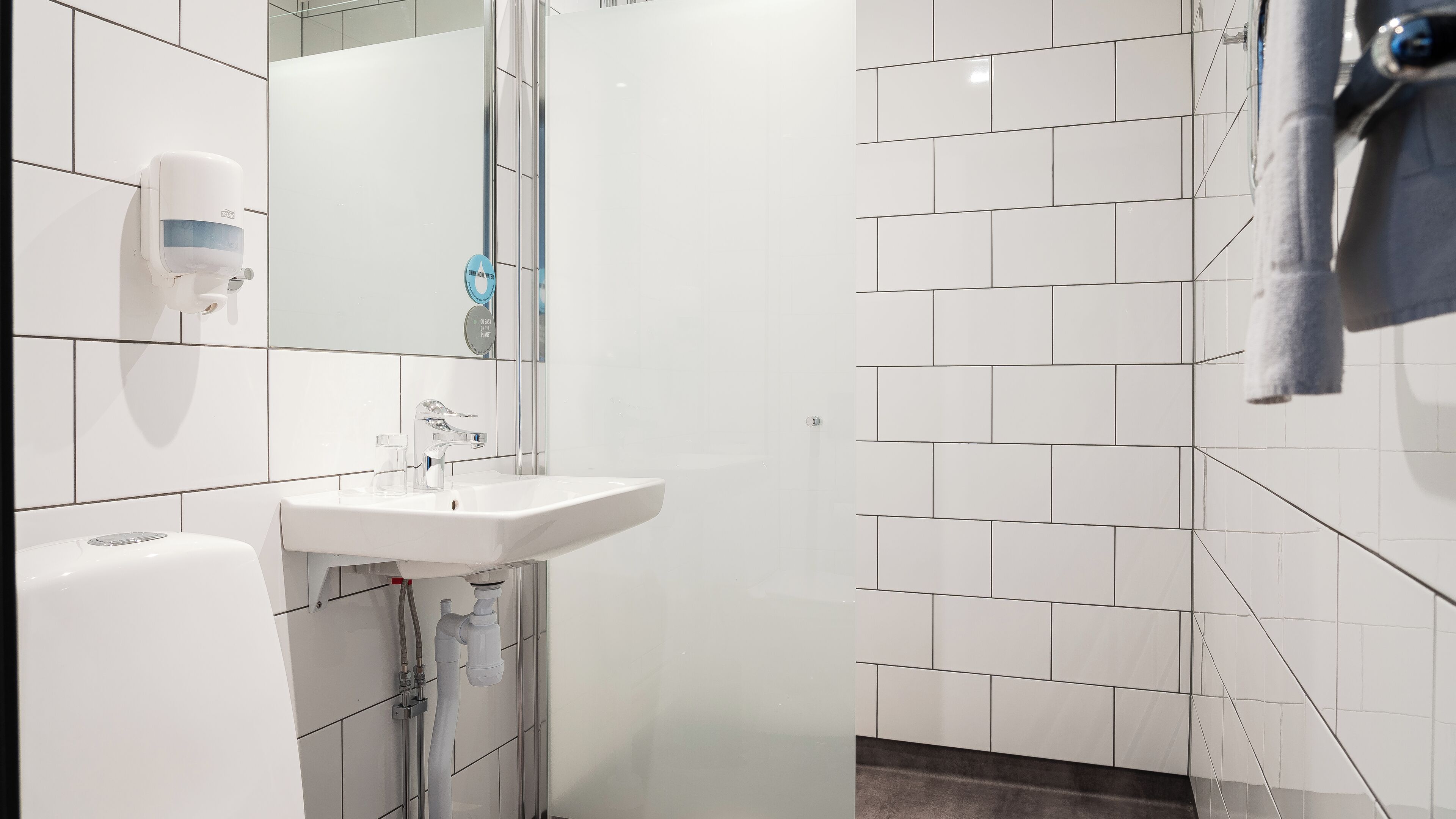 Un baño moderno con un lavamanos blanco, un espejo y una toalla colgada en la pared.