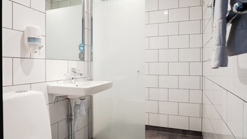 Un baño moderno con un lavamanos blanco, un espejo y una toalla colgada en la pared.