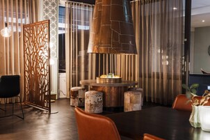 Een eetruimte met een ronde tafel, stoelen, een decoratieve scheiding en een hanglamp.