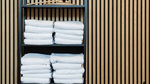 A black metal shelf with white towels and a plant against a striped wooden wall. - Comfort Hotel Skelleftea (Skelleftea)