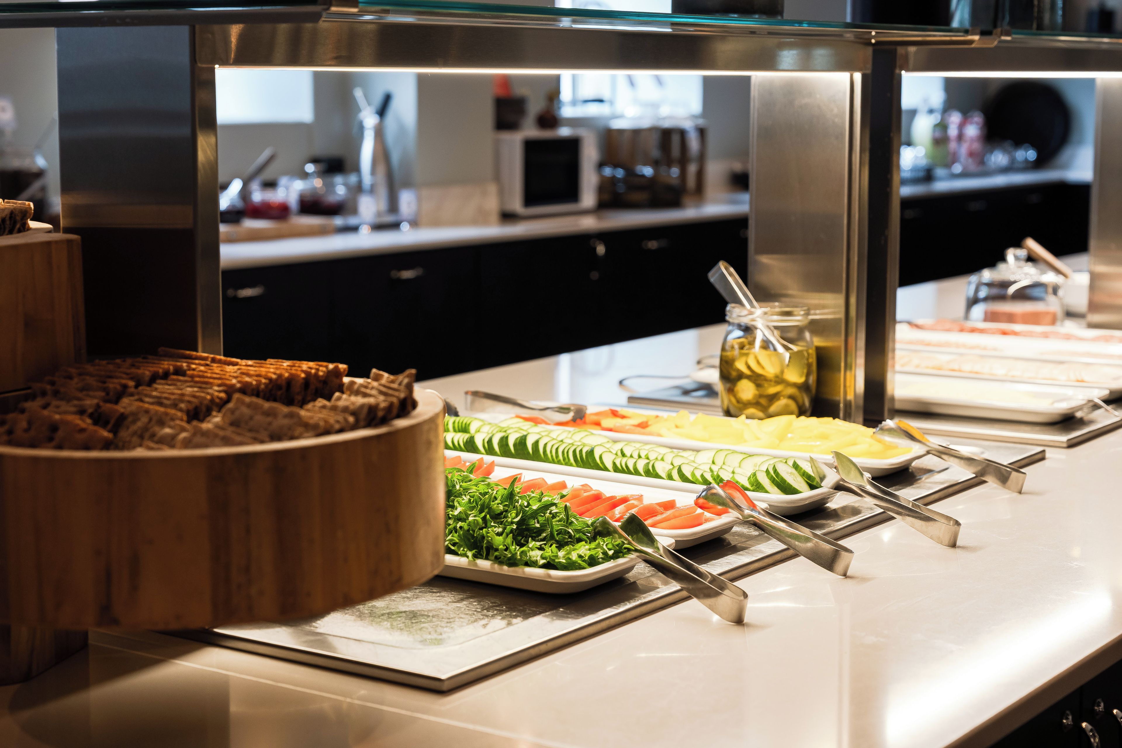 A buffet with various food items including sliced vegetables, fruits, and a bowl of bread.
