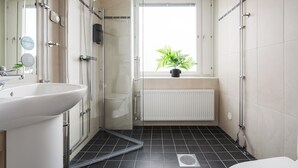 A modern bathroom with a glass shower enclosure, a white sink, and a potted plant by the window. - Comfort Hotel Skelleftea (Skelleftea)