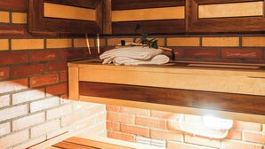 A sauna with wooden benches, a brick wall, and a towel rack. - Comfort Hotel Skelleftea (Skelleftea)