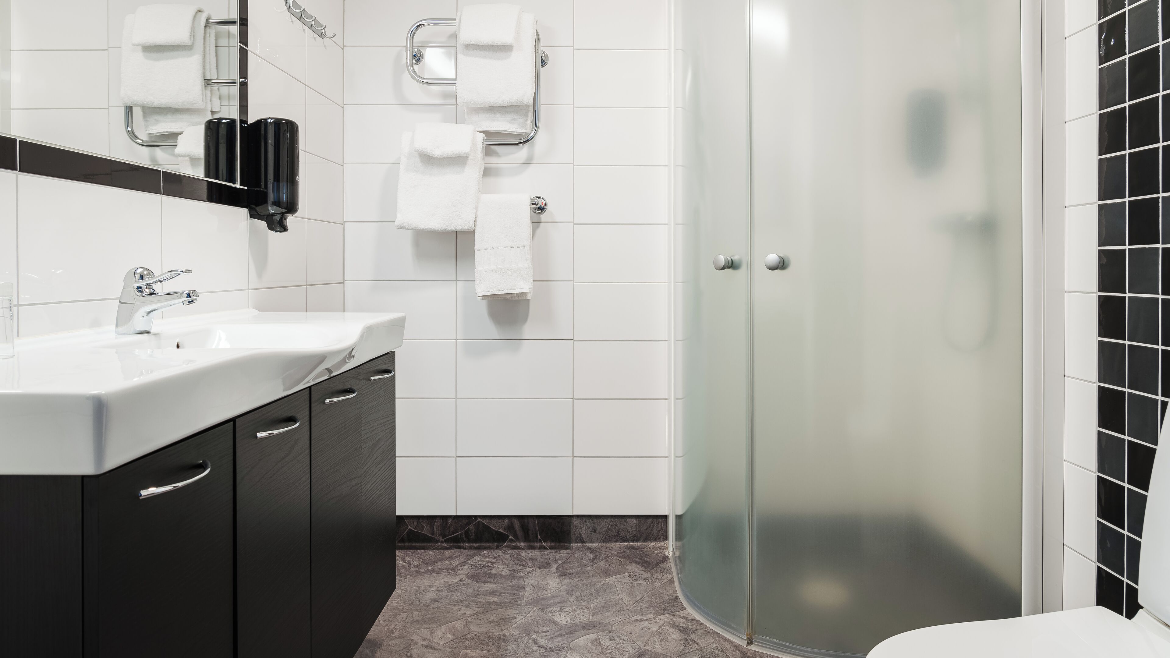 A modern bathroom with a glass-enclosed shower, a white sink, and a dark-toned vanity.