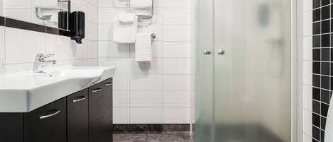 A modern bathroom with a glass-enclosed shower, a white sink, and a dark-toned vanity.