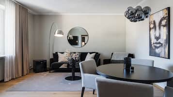 A modern living room with a round dining table, a sofa, a floor lamp, and a large mirror on the wall.