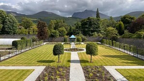 A formal garden with a central gazebo, neatly trimmed hedges, and a pathway leading to a mountain backdrop. - Inverlochy Castle (Fort William)