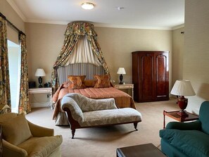 A bedroom with a bed, a chair, a wardrobe, and a nightstand with lamps. - Inverlochy Castle (Fort William)