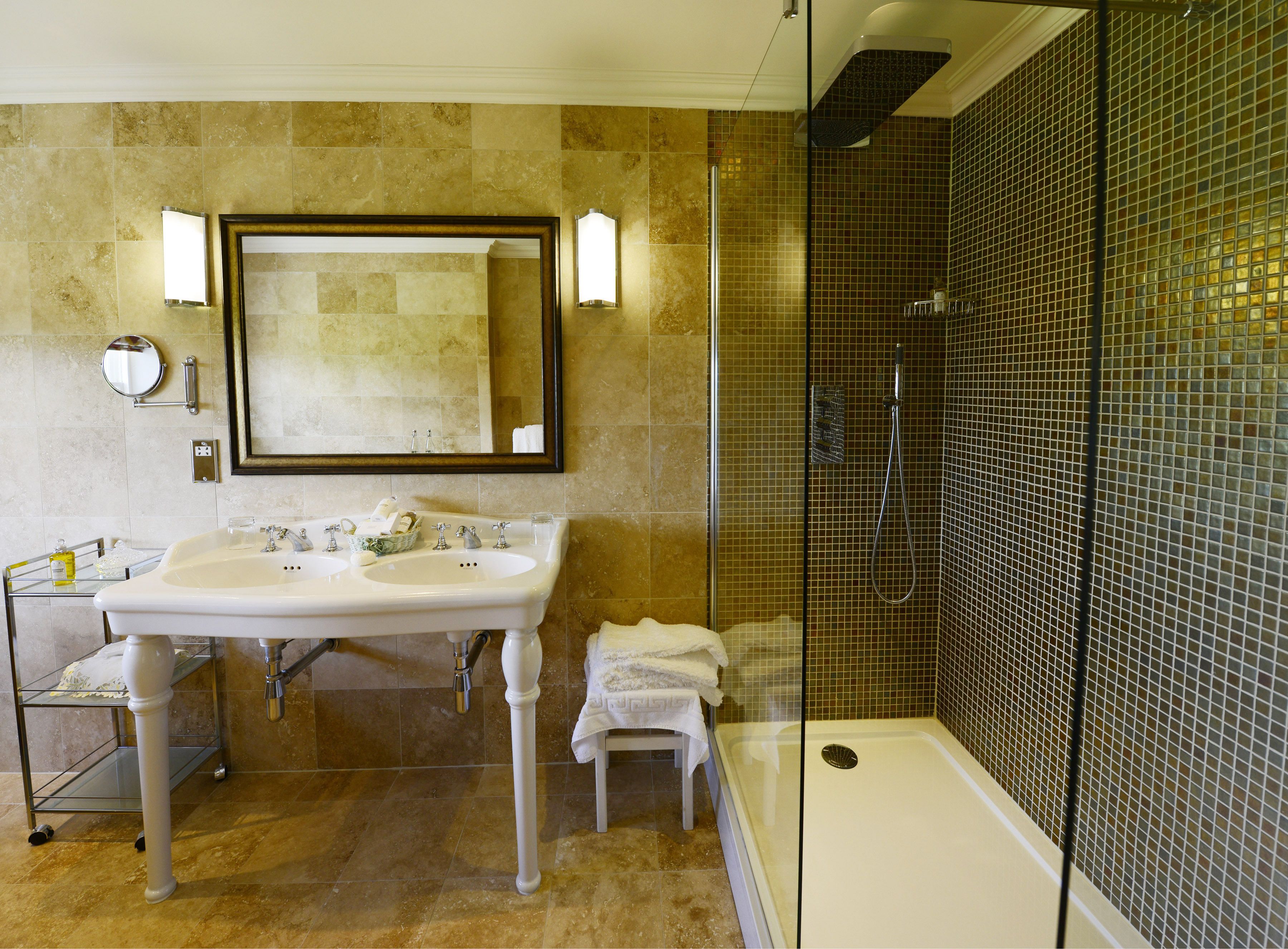 Une salle de bain dotée d’un grand miroir, de deux lavabos, d’une douche à parois de verre et d’une baignoire blanche.
