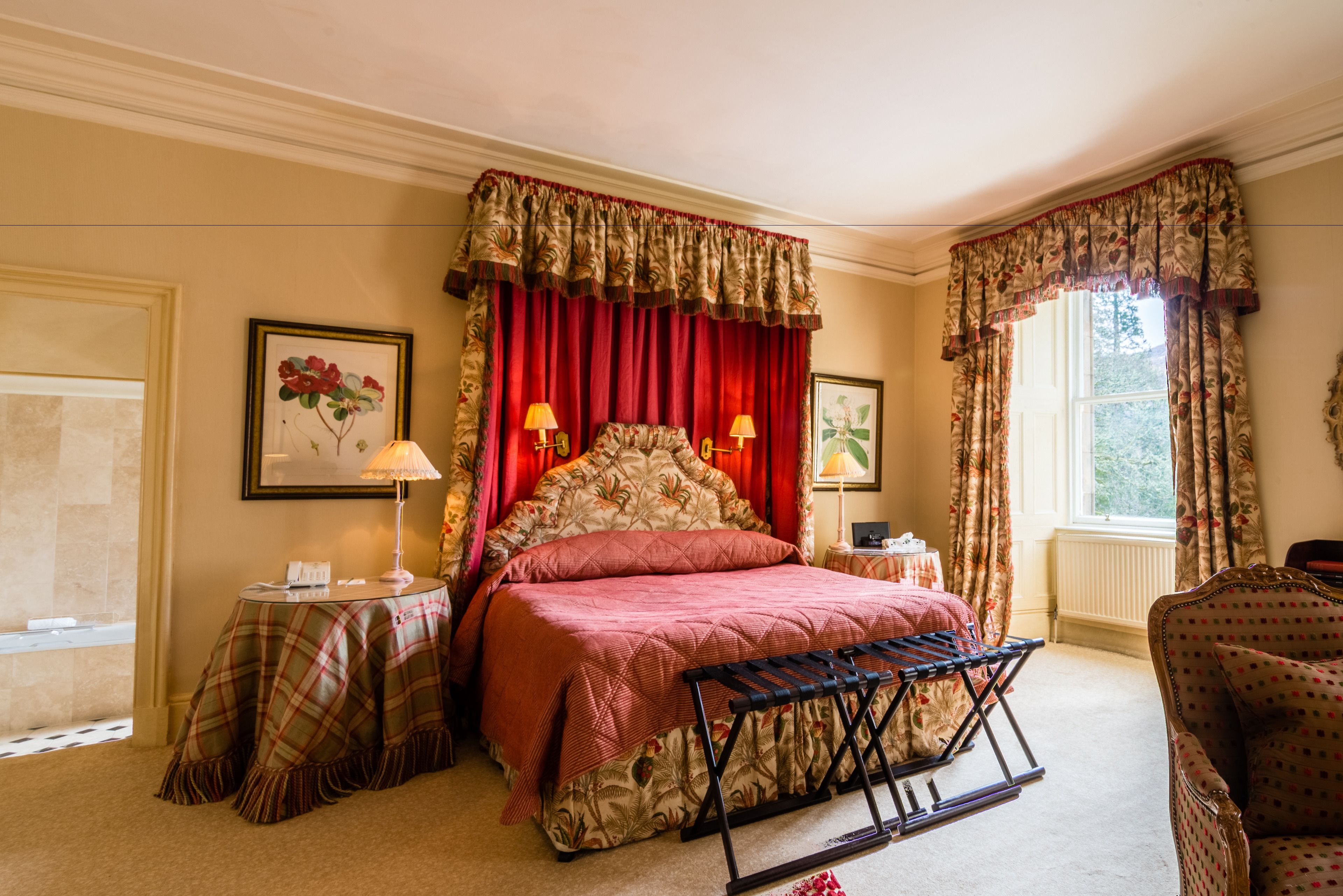 A bedroom with a bed, a nightstand, a lamp, a chair, and a window with curtains.