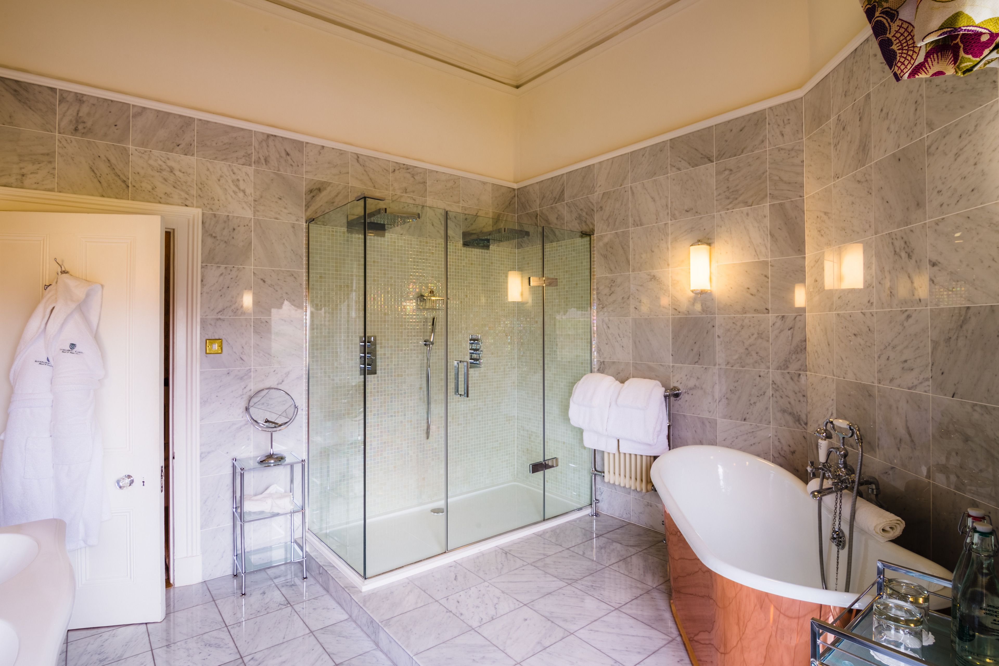 Un baño moderno con ducha envuelta en vidrio, una bañera independiente y un tocador con espejo.