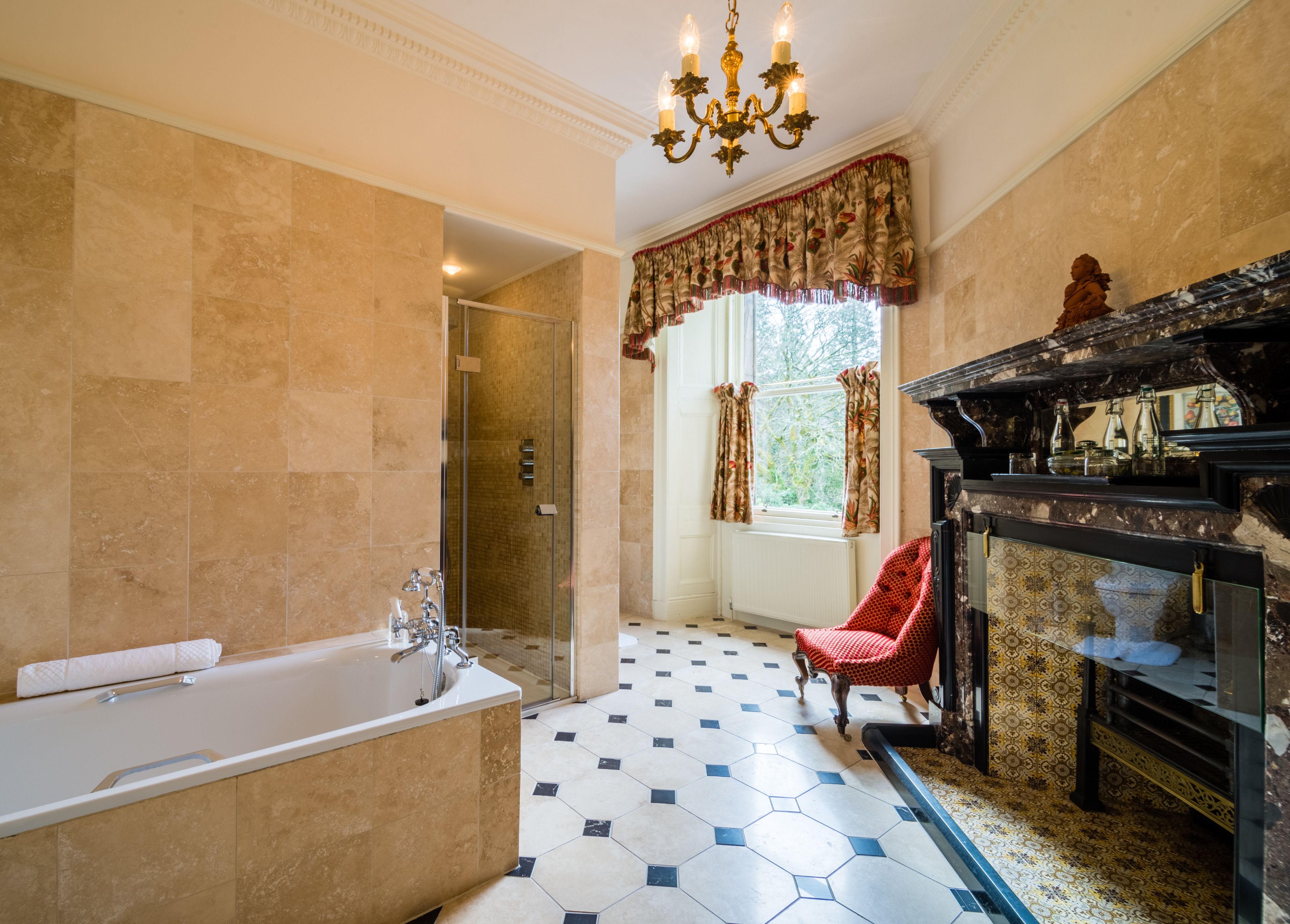 A bathroom with a large bathtub, a shower, and a red chair.