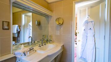 Un baño con lavamanos doble, un espejo grande y una bata colgada en la puerta.