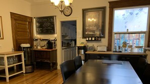 Une cuisine moderne avec une table en bois, des chaises, une machine à café et un tableau noir servant de menu.
