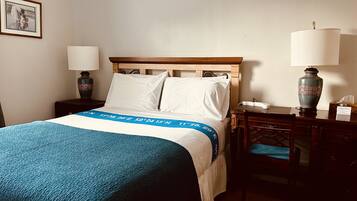 Una habitación de hotel con una cama, dos mesitas de noche, una silla y un escritorio.