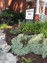 A sign for Rideau Inn with a brick building in the background.