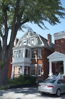A two-story brick building with a bay window and a porch.