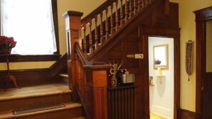 Un escalier en bois avec une rampe et une petite table ornée d’objets décoratifs placée au centre.