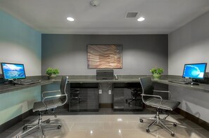 Un espace de bureau moderne comprenant deux bureaux, chacun équipé d’un ordinateur et d’une chaise, ainsi qu’un élément décoratif mural.