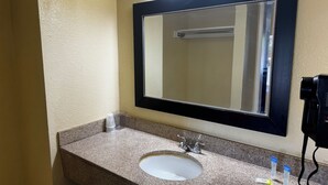 A bathroom with a granite countertop, a white sink, a black-framed mirror, and a wall-mounted phone. - GuestPlace Inn & Suites (Redding)