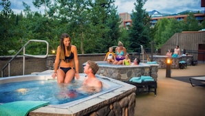 A hot tub area with stone walls and a view of trees and buildings in the background. - Beaver Run Resort & Conference Center (Breckenridge)