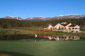 A golf course with a house and a mountain backdrop.