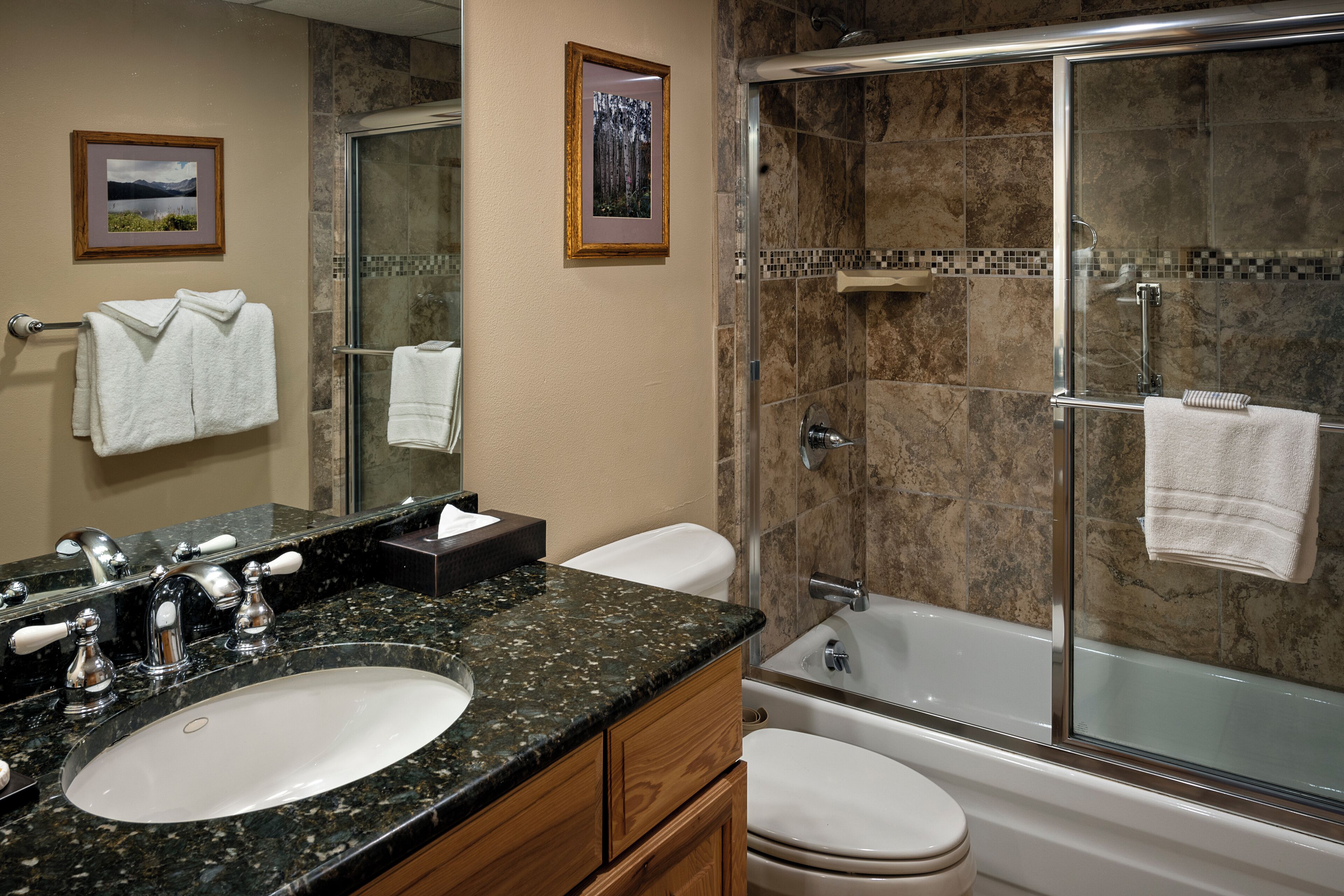 A bathroom with a sink, mirror, towel rack, and a glass-enclosed shower area.