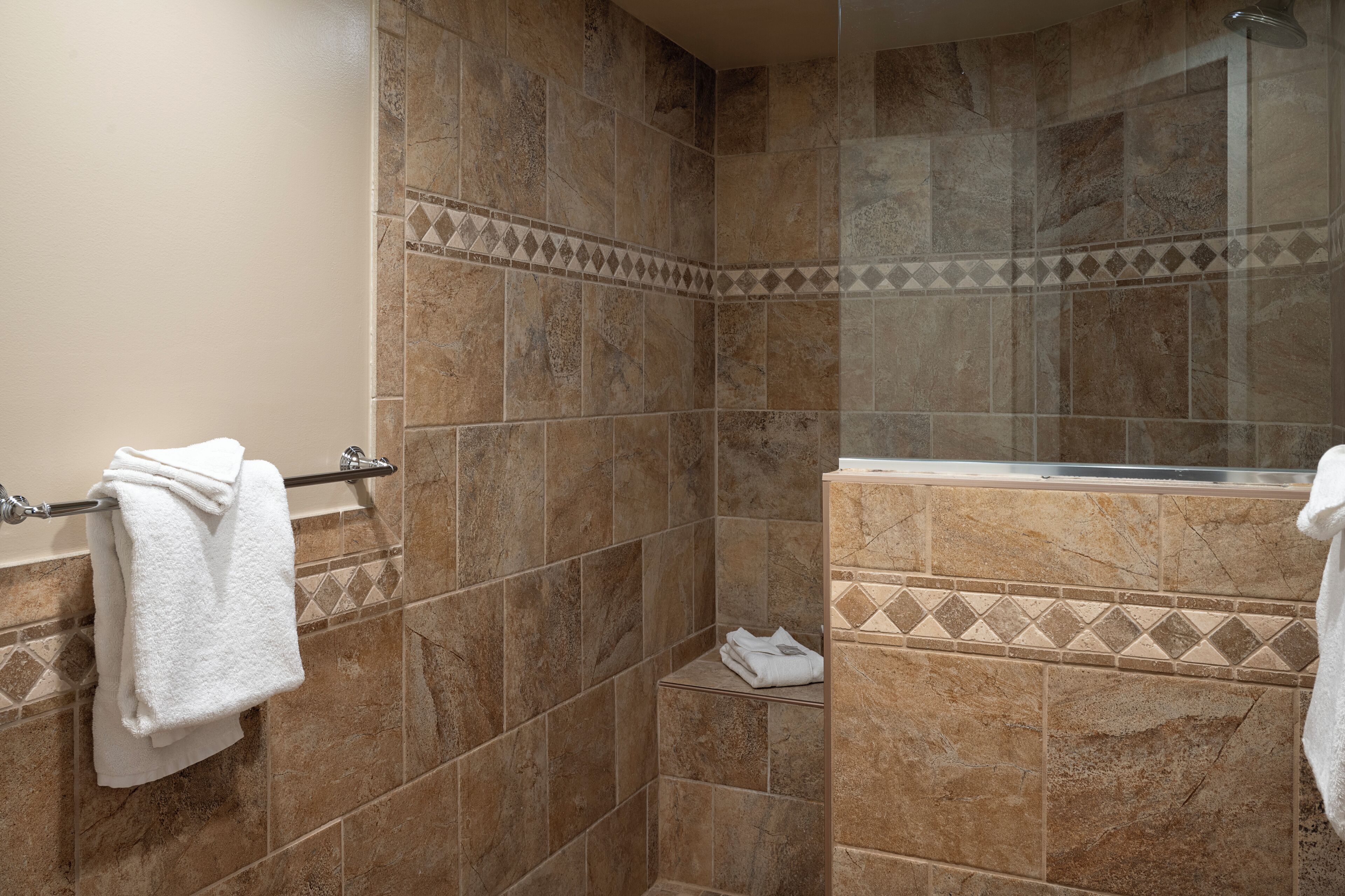 A bathroom with a shower, tiled walls, a towel rack, and a shelf.