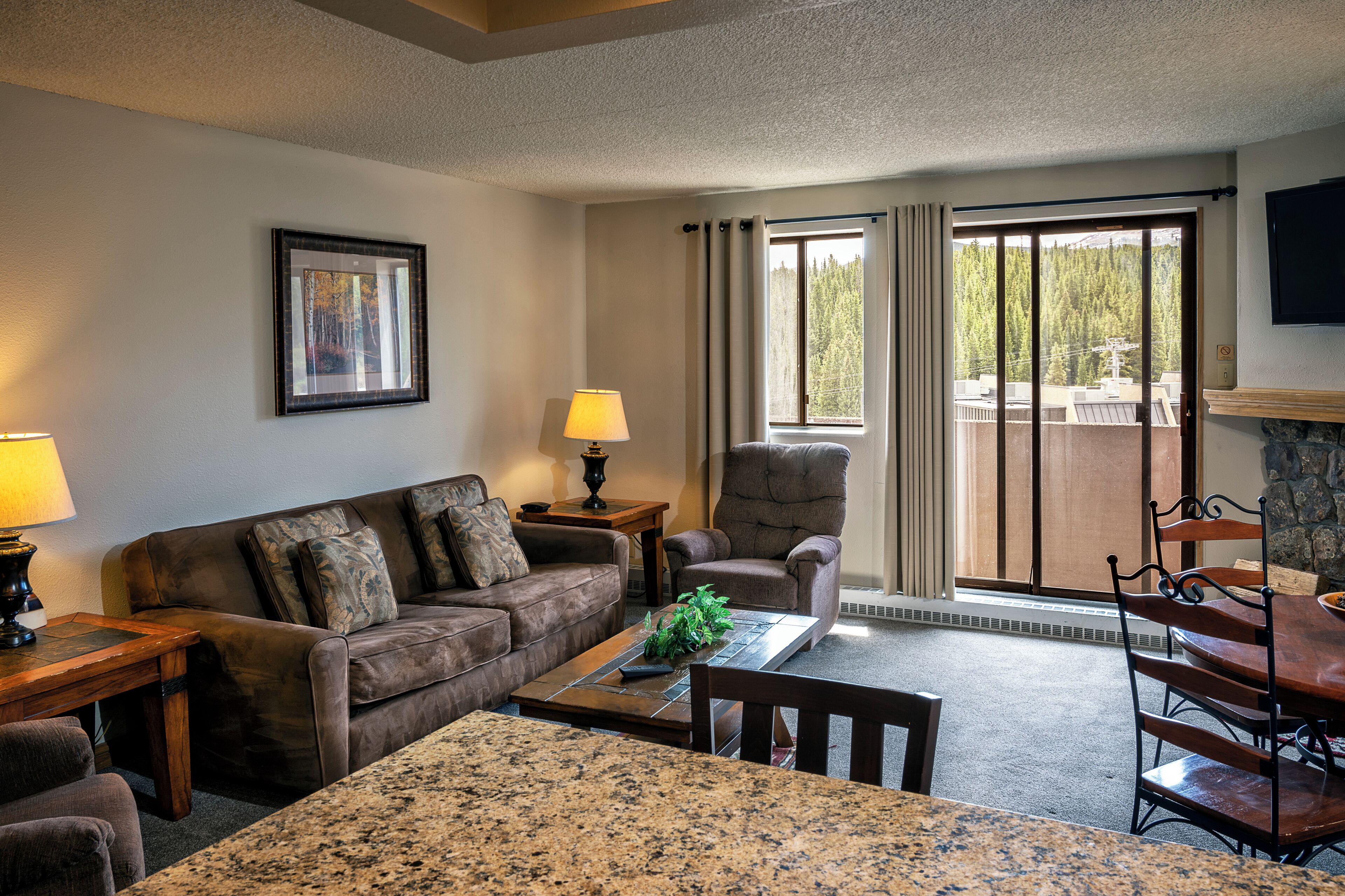 A cozy living room with a sofa, armchair, coffee table, and dining table.