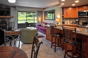 A spacious kitchen with a large island, wooden cabinets, and a stone fireplace.