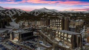 A hotel with multiple buildings, a parking lot, and a mountainous backdrop. - Beaver Run Resort & Conference Center (Breckenridge)